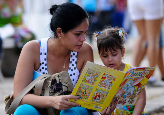 Una joven lee junto a su niña un libro de cuentos recién comprado en la Feria del Libro en La Habana. /Foto: Calixto N. Llanes