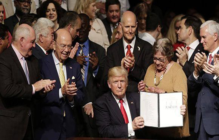 Donald Trump firma la orden ejecutiva que da marcha atrás a algunas de las medidas que impulsaron las relaciones Cuba- Estados Unidos. Foto: AP.