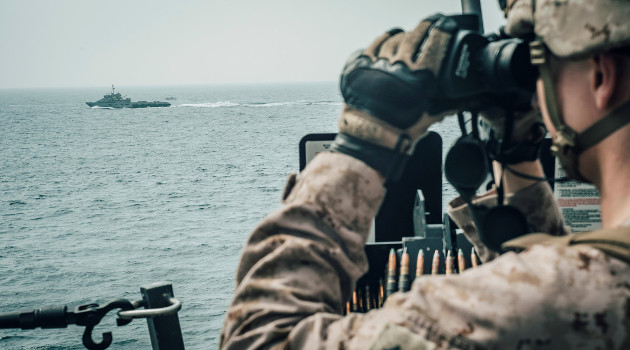 Un marine a bordo del buque USS John P. Murtha observa con prismáticos los movimientos de una embarcación iraní de ataque rápido en el estrecho de Ormuz, frente a Omán, 18 de julio de 2019. /Foto: Donald Holbert (Reuters)