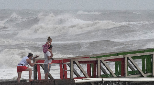Una familia observa la marejada ciclónica provocada por el huracán Hanna desde un muelle en Galveston, Texas (EE.UU.), el 25 de julio de 2020. /Foto: Adrees Latif (Reuters)