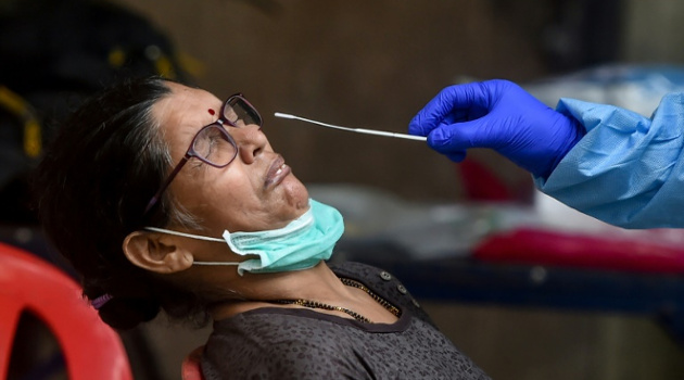 Un trabajador sanitario toma una muestra de una mujer para realizar una prueba de COVID-19 el 16 de julio de 2020 en Bombay, India. /Foto: Punit Paranjpe (AFP)