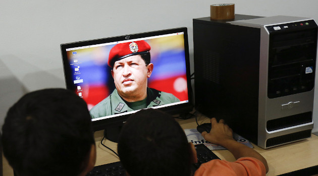 Niños venezolanos ven un fondo de pantalla de Hugo Chávez, en Caracas, 26 de noviembre de 2013. /Foto: Carlos Garcia Rawlins / Reuters