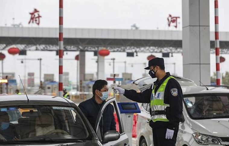 Un oficial de policía verifica la temperatura de un conductor en una carretera en Wuhan, en la provincia central china de Hubei, el 24 de enero de 2020. /Foto: AFP