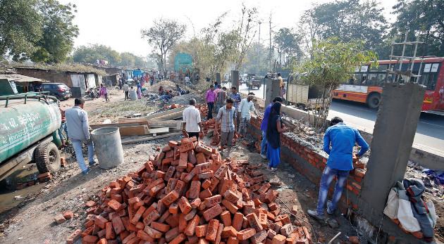 Albañiles construyen un muro a lo largo de la ruta prevista que recorrerá Donald Trump cerca de los barrios marginales en la ciudad de Ahmedabad, India, el 13 de febrero de 2020. /Foto: Amit Dave (Reuters)