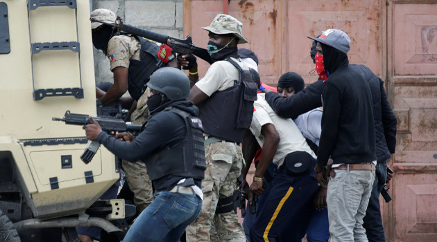 Manifestantes y policías detrás de un blindado de la Policía durante el tiroteo en Champ de Mars, Puerto Príncipe, Haití, el 23 de febrero de 2020. /Foto: Andrés Martínez Casares (Reuters)