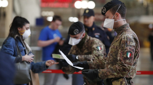 Agentes de la Policía y soldados revisan a los pasajeros que salen de una estación de trenes de Milán (Italia), 9 de marzo de 2020. /Foto: Antonio Calanni (AP)