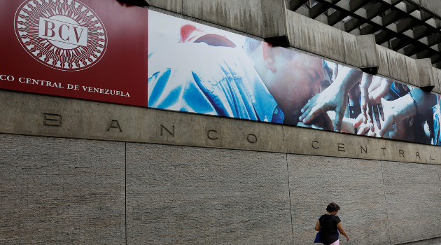 Una mujer camina al frente de la fachada del Banco Central de Venezuela en Caracas. /Foto: Marco Bello (Reuters)