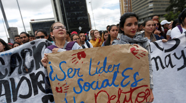 Manifestantes durante una protesta en Bogotá, Colombia, sostienen un cartel que dice "Ser un líder social es un delito". /Foto: Luisa Gonzalez (Reuters)