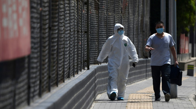 Dos hombres caminan en las afueras de un centro de deportes donde se hacen testeos masivos a personas que visitaron el mercado Xinfadi, en Pekín, el 15 de junio de 2020. /Foto: Noel Celis (AFP)