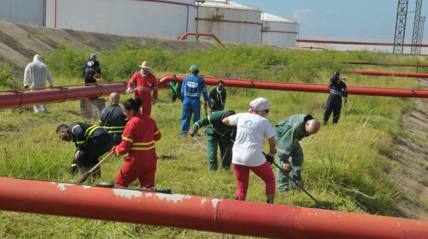 En el Refinería de Petroleo Camilo Cienfuegos trabajadores y fuerzas especializadas acometen la chapea del área industrial y extracción de residuales en las piscinas, respectivamente/Foto: Juan Carlos Dorado