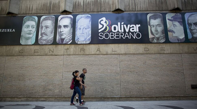 Una pareja camina frente a la fachada del Banco Central de Venezuela. /Foto: Ariana Cubillos (AP)