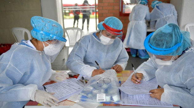 Trabajadores de la salud en plena tarea de registro de pruebas de Covid-19 realizadas en un autobús del barrio Kennedy en Bogotá, el 30 de junio de 2020. /Foto: Raúl Arboleda (AFP)
