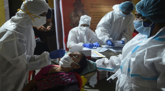 Personal sanitario toma una muestra de mucosa nasal a una mujer para realizar una prueba de detección del coronavirus. Bombay, India, el 16 de septiembre de 2020. /Foto: Punit Paranjpe (AFP)