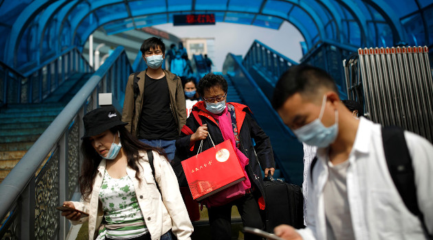 Personas con mascarillas protectoras cerca de una estación de tren de Pekín (China), 1 de octubre de 2020. /Foto: Carlos Garcia Rawlins (Reuters)