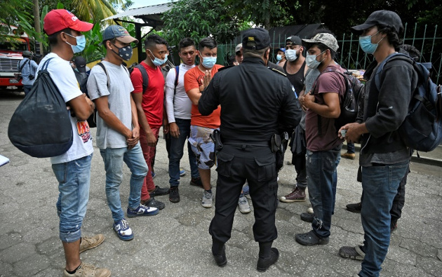 Un policía de inmigración dialoga con migrantes hondureños el 3 de octubre de 2020 en un refugio en Guatemala. /Foto: Alfredo Estrella (AFP) 
