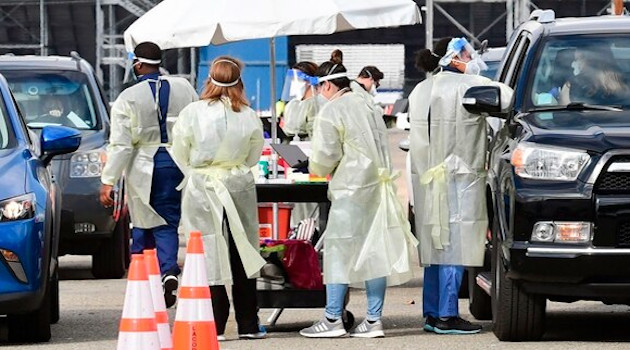 Personal de atención médica vestido con equipo de protección personal ayuda a vacunar a ciudadanos, en el Fairplex, en Pomona, California el 22 de enero del 2021. /Foto: AFP