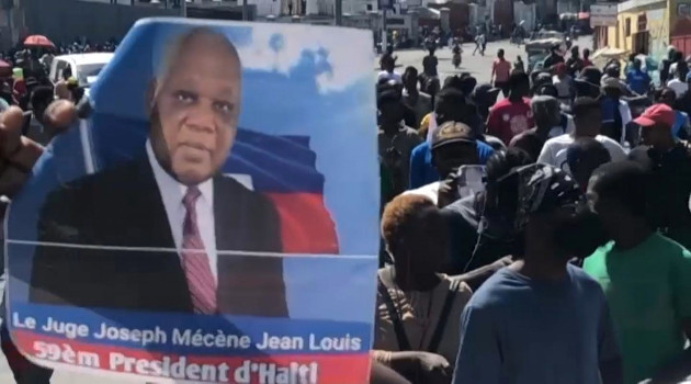 Manifestantes portan cartel con la imagen de Joseph Mécène, el presidente nombrado por la oposición de Haití. /Foto: AFP